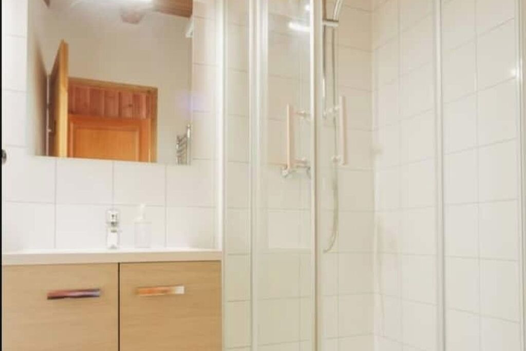 Une salle de bain avec une douche à parois de verre, un meuble en bois et un miroir.