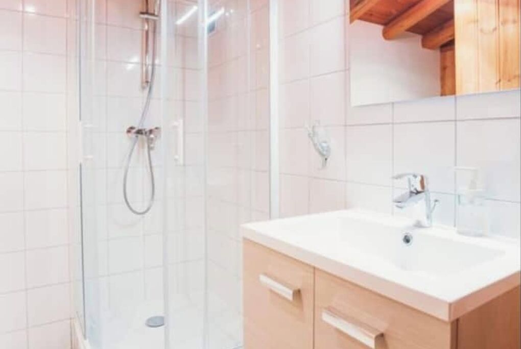 Un bagno moderno con doccia vetrata, lavandino bianco e mobili in legno.