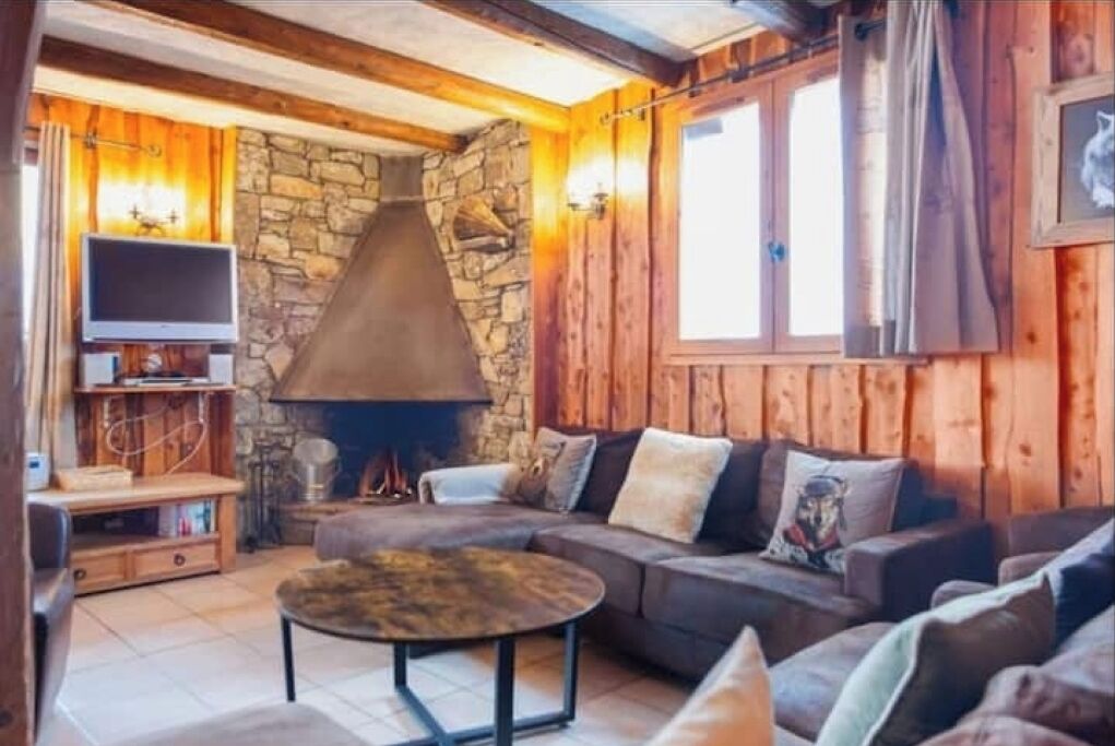 Un salon chaleureux avec une cheminée en pierre, des murs en bois et un canapé confortable.
