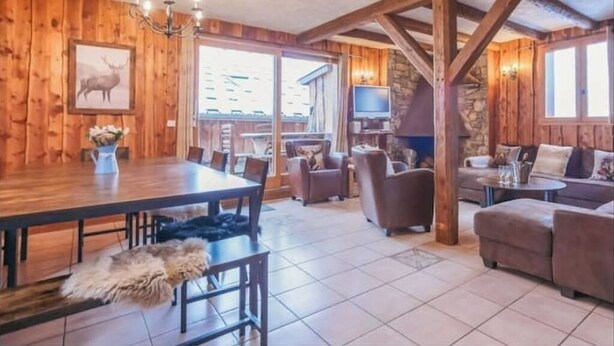 A spacious room with a wooden dining table, comfortable seating, and a stone fireplace. - 4-bedroom chalet with jacuzzi and sauna (La Plagne Tarentaise)