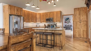 A modern kitchen with wooden cabinets, stainless steel appliances, and a central island with bar stools.