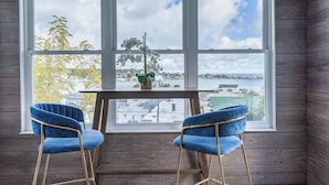 A room with a large window, two blue chairs, and a small table with a plant.