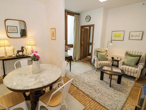 A living room with a round table, two armchairs, a sofa, and a coffee table. There is a door leading to another room, a clock on the wall, and a mirror on the wall. - Diamond Lodge (Stafford)