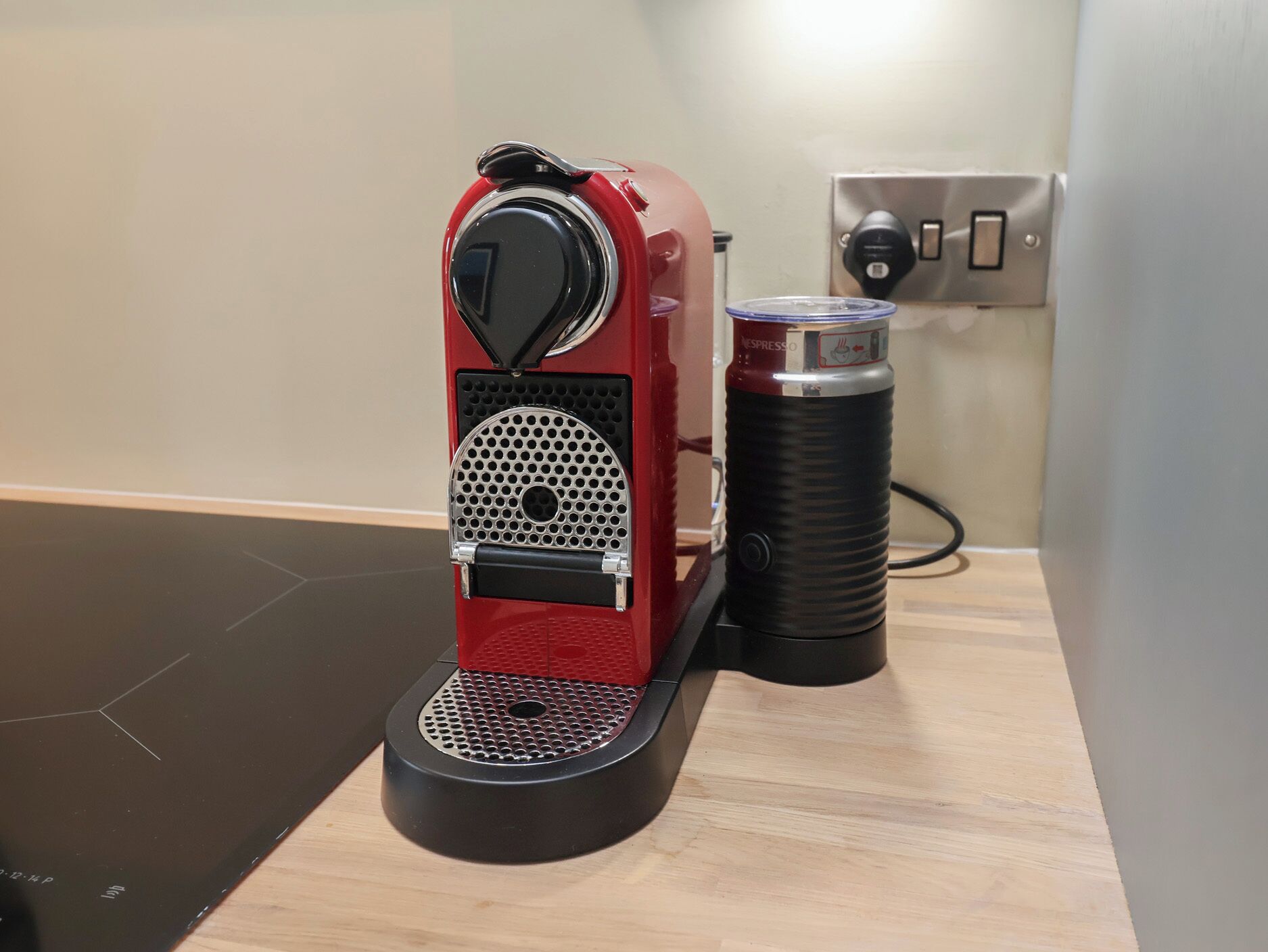 A red espresso machine with a coffee pod holder on a wooden countertop.