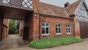 A traditional brick building with a tiled roof, a covered entrance, and a small garden area.