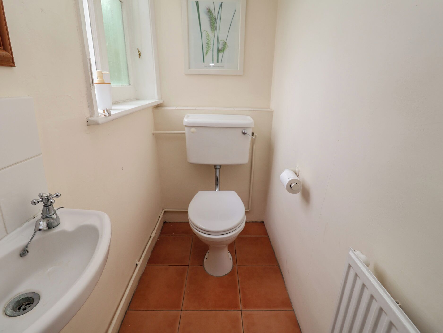 A small, clean bathroom with a white sink, toilet, and radiator.