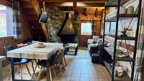 L’intérieur d’un chalet accueillant, avec une cheminée en pierre, des meubles en bois et une bibliothèque.