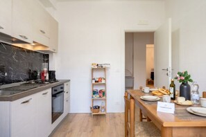 Een moderne keuken met een marmeren spatwand, een ingebouwde oven en een eethoek met een houten tafel gedekt voor twee personen.