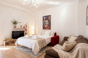 Een moderne hotelkamer met een bed, een rode bank, een televisie en een schilderij aan de muur.