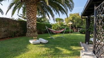 Ein gepflegter Garten mit einer Hängematte, Kissen und einer Palme.