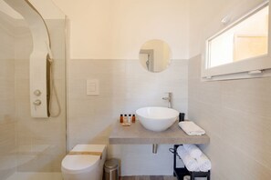 A modern bathroom with a large white sink, a round mirror, a shower enclosure, and a toilet. - Covi del Viaggiatore 2 – Modern Comfort, Timeless Charm (Bari)