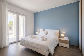 A bedroom with a bed, bedside tables, and a view through the glass door.