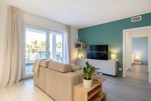 A modern living room with a sofa, TV, and a plant.
