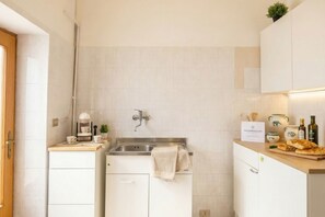 A compact kitchen with a sink, countertop, and cabinets.
