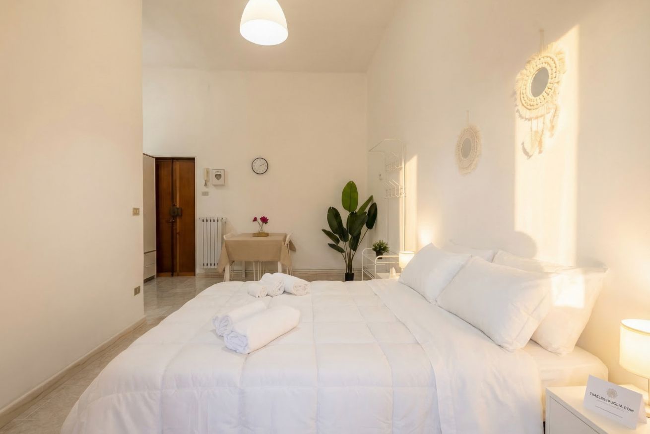 Un dormitorio con cama, mesita de noche, lámpara y un reloj en la pared.