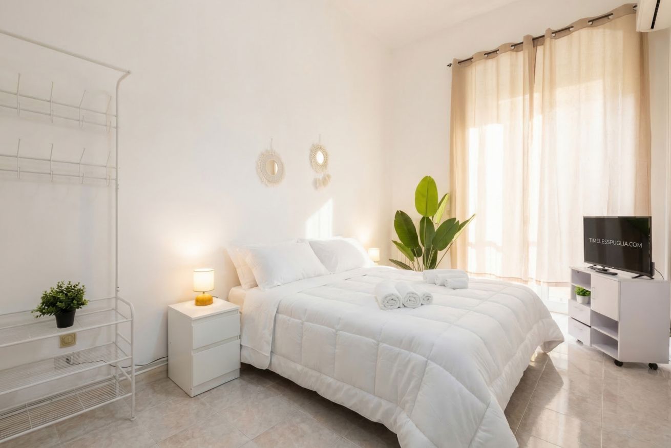 Una camera d'albergo con un letto, un comodino, una TV e una pianta.