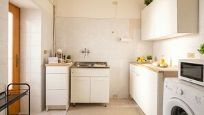 A compact kitchen with a washing machine, a sink, and cabinets.