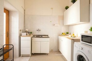 A compact kitchen with a washing machine, a sink, and cabinets.