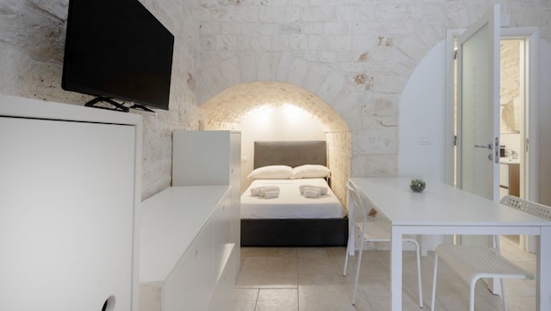 Une chambre à coucher moderne avec un lit, un bureau et un téléviseur.