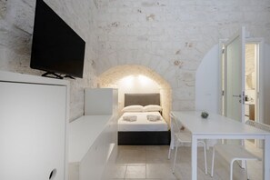 A modern bedroom with a bed, a desk, and a TV. - Nathan House - Cozy Stone Apartment (Casamassima)