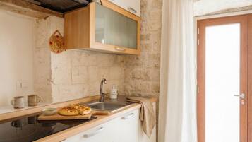 Una cocina con encimera de madera, estufa, pileta y un armario sobre la pileta.