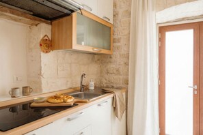 Una cocina con encimera de madera, estufa, pileta y un armario sobre la pileta.