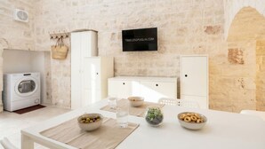Una cocina moderna con pared de piedra, lavadora y zona de comedor con mesa para dos.