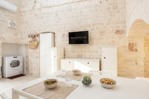 Una cocina moderna con pared de piedra, lavadora y zona de comedor con mesa para dos.