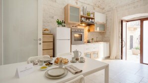 Una cocina moderna con armarios blancos, horno integrado y un comedor con mesa dispuesta para el desayuno.