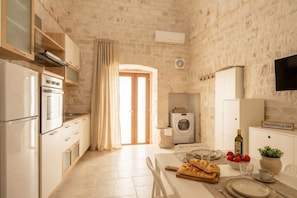 Una cocina con horno empotrado, lavadora y comedor con una mesa lista para dos.