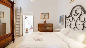 A bedroom with a large bed, a wooden dresser, a mirror, and a painting on the wall.