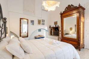 Une chambre à coucher avec un grand lit, une commode en bois, un miroir et un lustre.