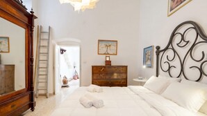 Quarto com uma cama grande, penteadeira de madeira, espelho e um quadro na parede.