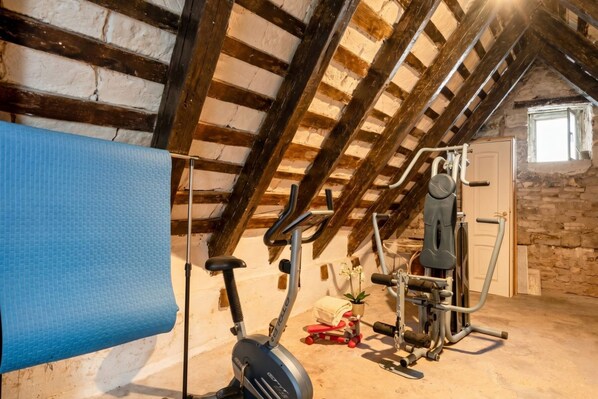 Une chambre mansardée avec un ventilateur de plafond, du matériel de sport et une fenêtre.