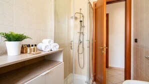 Un bagno moderno con doccia vetrata, un vanità in legno e una pianta in vaso.