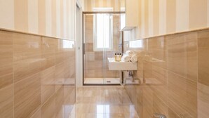 Une salle de bain moderne avec une douche en verre, un lavabo doté d’accessoires de toilette et des murs à rayures.