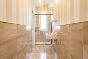 A modern bathroom with a glass shower enclosure, a sink with toiletries, and striped walls.