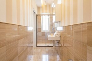 A modern bathroom with a glass shower enclosure, a sink with toiletries, and striped walls.