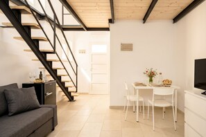 Una sala moderna con una escalera, un comedor con mesa y sillas, y un sofá.