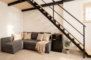 A modern living room with a grey sectional sofa, a black metal staircase, a small black cabinet, and a potted plant. - Casa di Lu - Urban Classic  (Bari)
