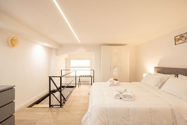 A bedroom with a bed, a desk, a chair, and a window.