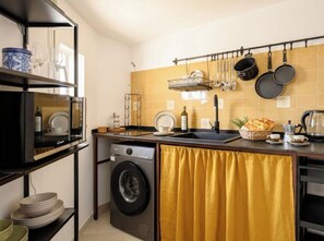 Una cocina compacta equipada con lavadora, lavamanos y cafetera.