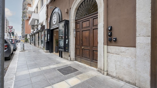 Vista d'un carrer amb un edifici que té una porta de fusta gran i un rètol amb un número.
