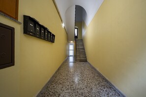 A hallway with a carpeted floor, a staircase, and a row of mailboxes on the wall.