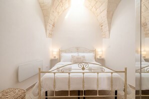 A bedroom with a bed, white walls, a brick ceiling, and two bedside lamps. - Mia & Mimi – Accogliente Rifugio nel Centro Storico (Ostuni)