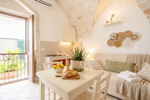 A cozy kitchen with a dining table, a plant, and a balcony with plants. - Mia & Mimi – Accogliente Rifugio nel Centro Storico (Ostuni)