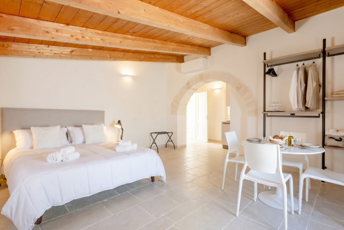 Una camera da letto con un letto grande, un tavolo da pranzo con sedie e un soffitto in legno.