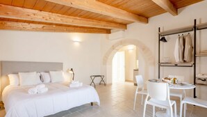 A bedroom with a large bed, a dining table with chairs, and a wooden ceiling. - Tower Palace 201 - Historic Modern Lofts (Bari)