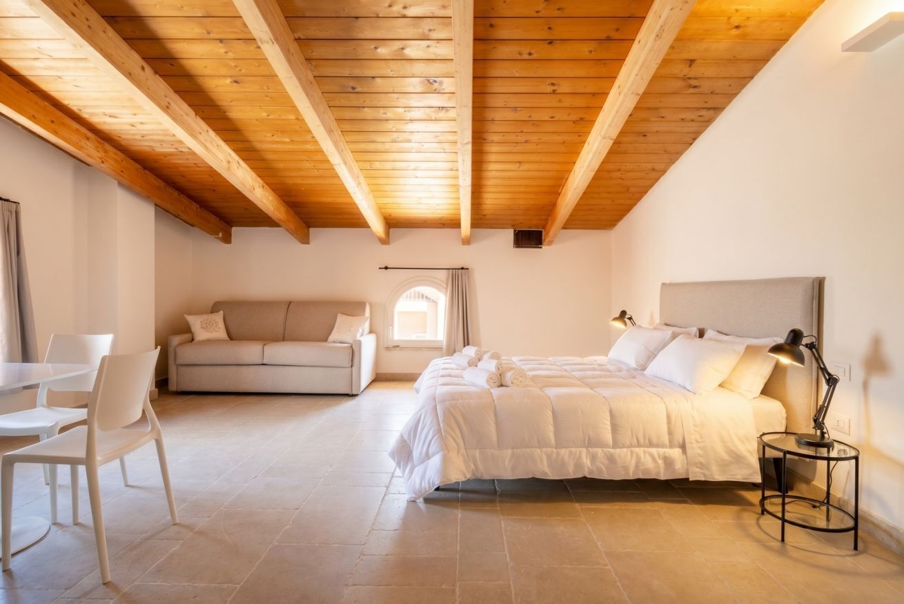 Una camera da letto con un letto, un divano, un tavolo da pranzo con sedie e una lampada.