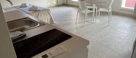 A kitchen with a built-in stove, a sink, and a dining area with a table and chairs.